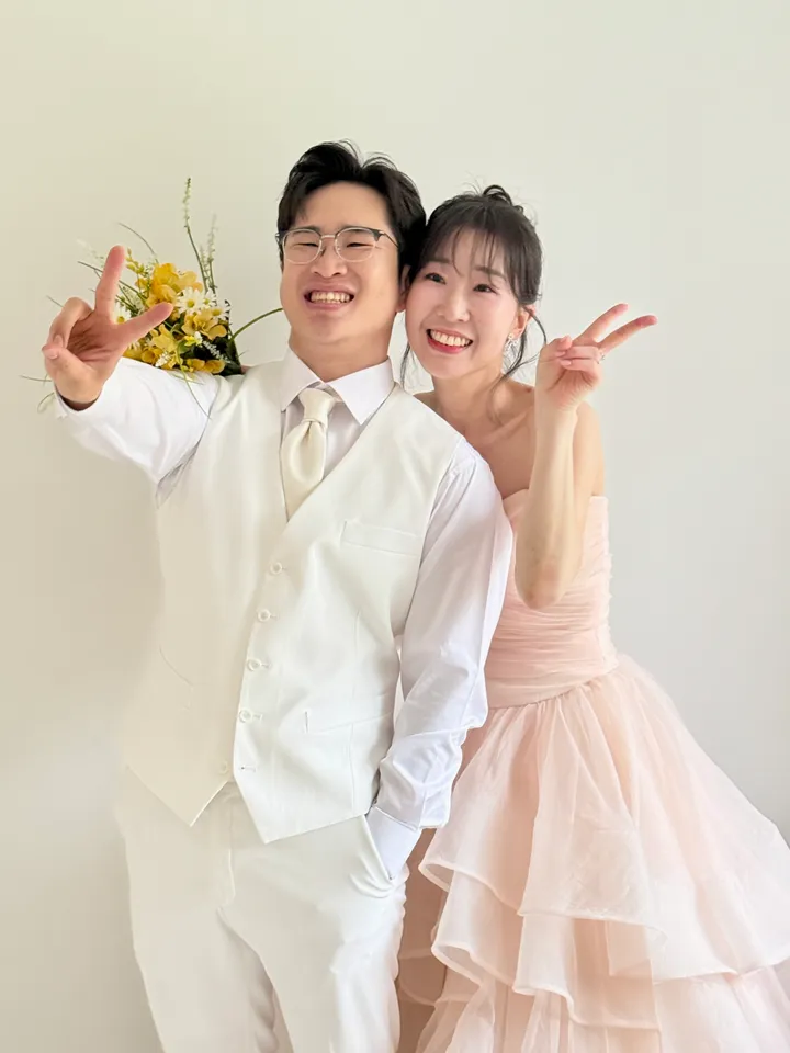 노란 꽃다발과 함께 브이를 하는 신랑과 신부