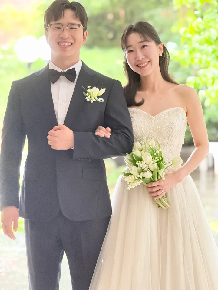 정원 앞에서 팔짱을 끼고 나란히 선 신랑과 신부