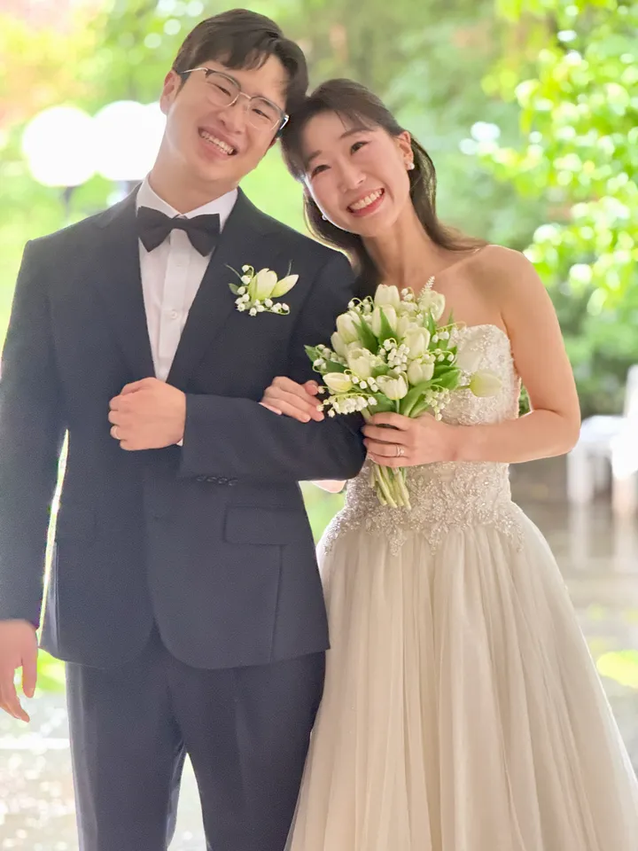 정원을 배경으로 팔짱을 끼고 웃는 신랑과 신부