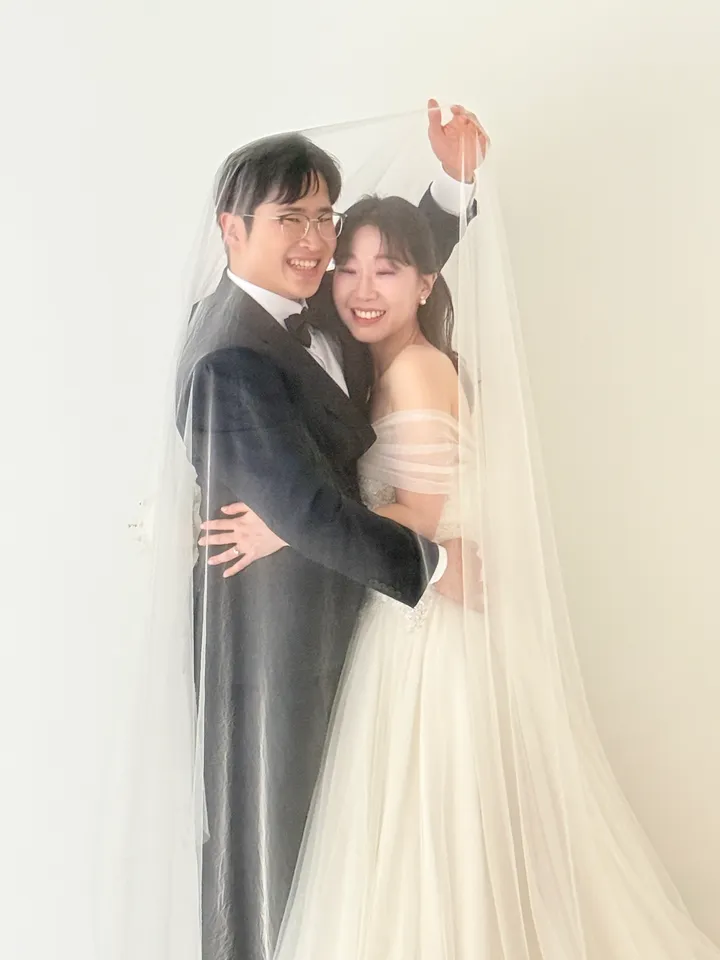 베일 아래에서 서로 안고 웃는 신랑과 신부