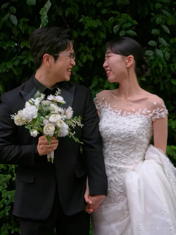 담쟁이 벽 앞에서 서로를 마주 보며 웃는 신랑과 신부