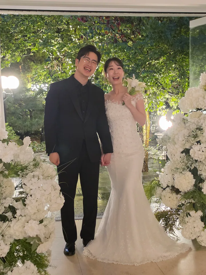 밤 정원의 흰 꽃 장식 사이에 선 신랑과 신부
